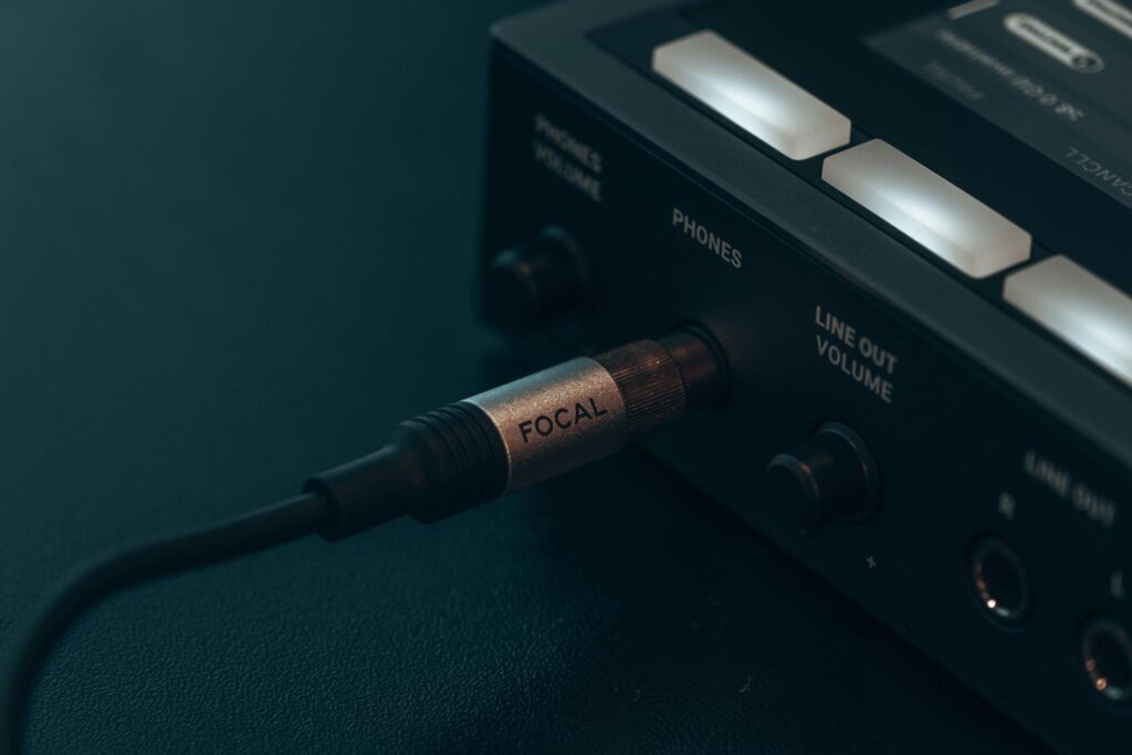 Detailed view of audio cable connected to electronic device, capturing modern technology essence.